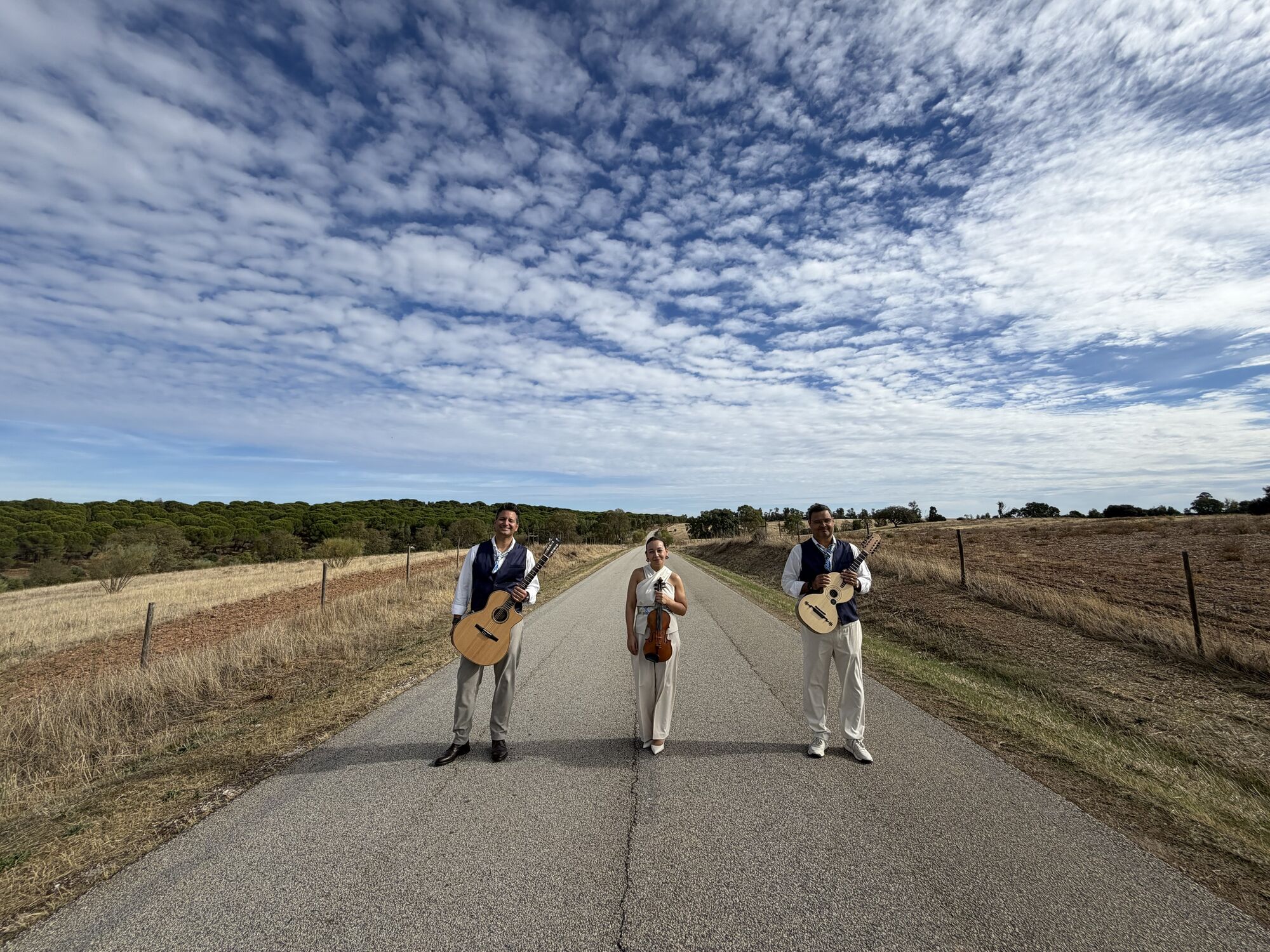 Os três músicos numa estrada do Alentejo, sob um céu muito aberto